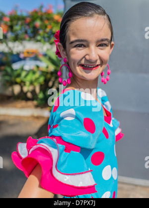 Un enfant dans son danseur hispanique de l'adolescence tôt pose dans son costume de danse flamenco traditionnel coloré, robe, boucles d'oreilles et d'un sèche avant. Banque D'Images