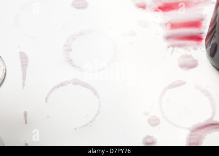 Les taches de vin rouge sur un fond blanc. Anneaux de verre de vin et des éclaboussures. Banque D'Images