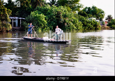 Delta du Mekong, Vietnam - Femme avec location d'être transporté en sampan à travers un affluent du Mékong dans la région du delta Banque D'Images