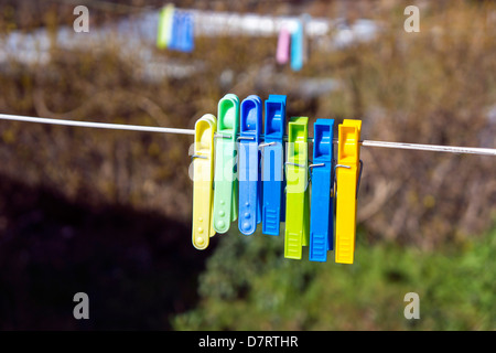 En plastique coloré pegs hanging sur ligne de lavage Banque D'Images