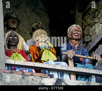 Des effigies en bois des morts, appelée tau-tau, protéger les lieux de sépulture des murs sculptés dans la roche de Torajaland sur l'île de Sulawesi en Indonésie. Banque D'Images