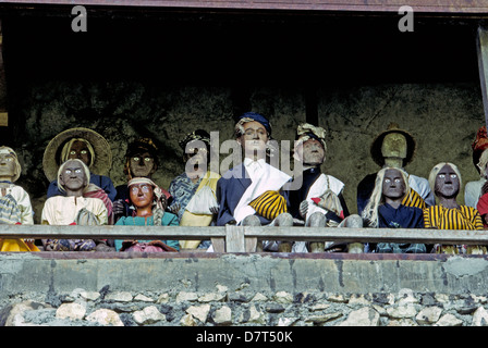 Des effigies en bois des morts, appelée tau-tau, protéger les lieux de sépulture des murs sculptés dans la roche de Torajaland sur l'île de Sulawesi en Indonésie. Banque D'Images