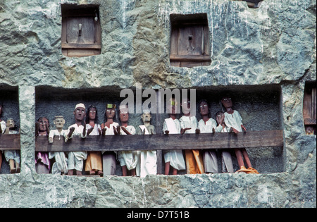 Des effigies en bois des morts, appelée tau-tau, protéger les lieux de sépulture des murs sculptés dans la roche de Torajaland sur l'île de Sulawesi en Indonésie. Banque D'Images