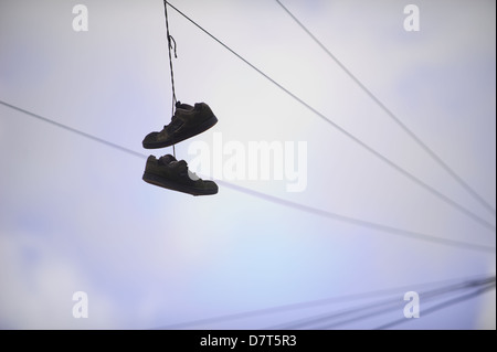 Une paire de baskets accrocher suspendue à un fil de téléphone dans la région de Cardiff, au Royaume-Uni. Banque D'Images