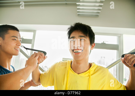 Jeune homme exerçant avec son entraîneur personnel dans la salle de sport Banque D'Images