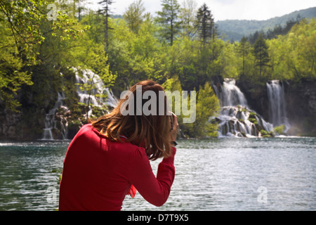 Femme touriste photographiant les chutes d'eau et les lacs du parc national des lacs de Plitvice, un site du patrimoine mondial de l'UNESCO, en Croatie en mai Banque D'Images