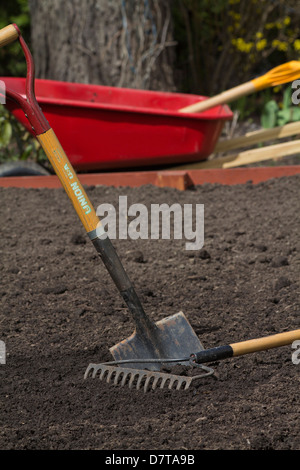 Une bêche dans le sol Spring fonctionne dans le jardin vide lit surélevé avec brouette au-dessus de personne format vertical aux États-Unis haute résolution Banque D'Images