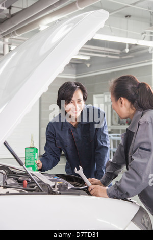 Mécaniciens travaillant sur voiture en atelier de réparation automobile Banque D'Images