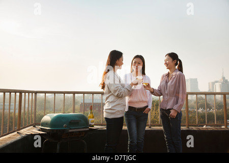 Les jeunes femmes Toasting each other on Rooftop au coucher du soleil Banque D'Images