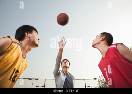 Jeter l'arbitre ballon en l'air, les joueurs de basket-ball pour se préparer à un saut Banque D'Images