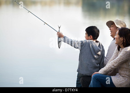 Boy admiring crochet de pêche en famille au lac Banque D'Images