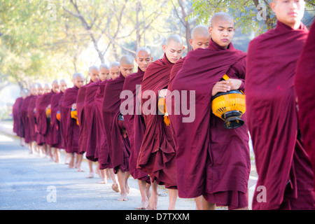 Les moines bouddhistes de marcher le long de la route pour recueillir des aumônes, près de Shwezigon Paya, Nyaung U, Bagan, Birmanie Banque D'Images