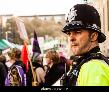 Les gens protestent contre la coalition gouvernement coupe comme un policier regarde sur. Banque D'Images