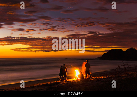 Personnes avec feu de bois flotté au coucher du soleil sur la plage de Playa Guiones, Nosara, Péninsule de Nicoya, Province de Guanacaste, Costa Rica Banque D'Images