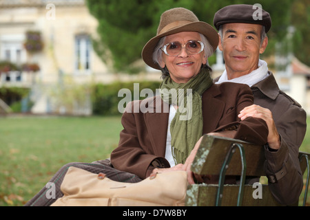Elegant couple assis sur un banc de parc Banque D'Images
