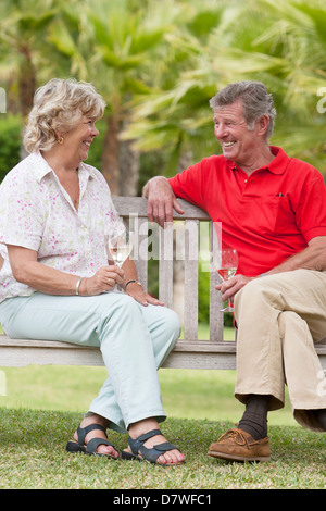 Couple de personnes âgées bénéficiant d'un verre de vin blanc dans leur jardin Banque D'Images