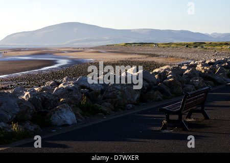 Seul un banc avec un fond d'une plage à marée basse avec des montagnes au loin. Banque D'Images