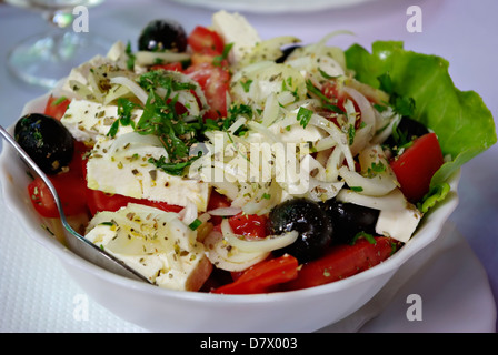 Salade grecque traditionnelle est composée de tomates, oignons, olives et fromage épices en plaque blanche avec une fourchette. Banque D'Images