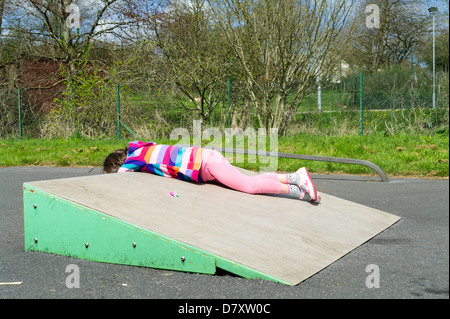 Fillette de six ans jouant sur la rampe de skate dans une aire de jeux. Banque D'Images