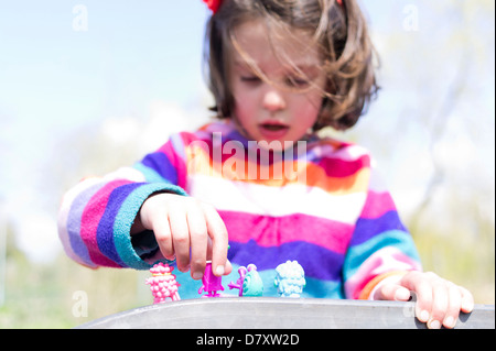 Fillette de six ans a jouer dehors avec des figurines Banque D'Images