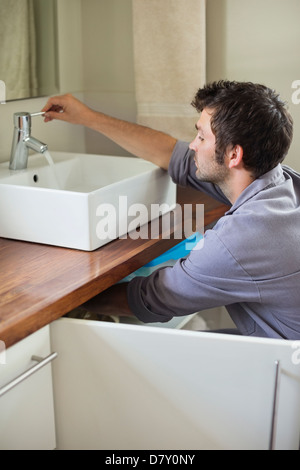 Plombier travaillant sur le lavabo de la salle de bains Banque D'Images