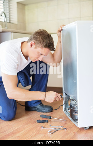 Réparateur travaillant sur appareil de cuisine Banque D'Images