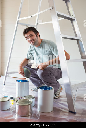 L'homme examinant les pots de peinture dans la chambre Banque D'Images