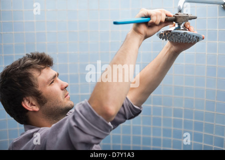 Plombier travaillant sur la tête de douche dans la salle de bains Banque D'Images