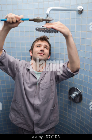 Plombier travaillant sur la tête de douche dans la salle de bains Banque D'Images