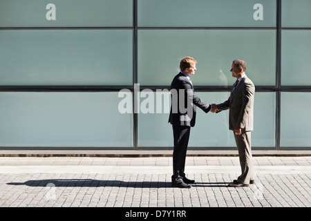 Businessmen shaking hands outdoors Banque D'Images