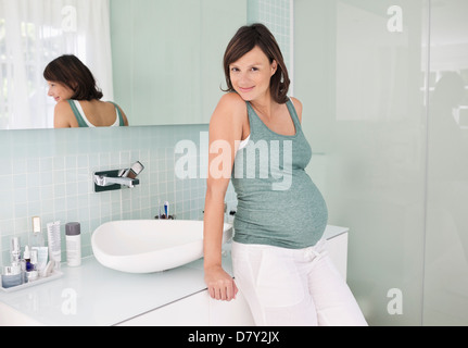 Pregnant woman leaning on bathroom sink Banque D'Images