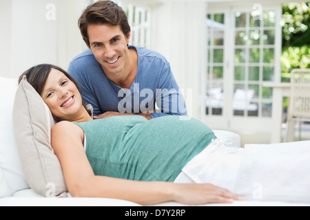 Homme assis à côté de femme enceinte se reposant sur le lit Banque D'Images
