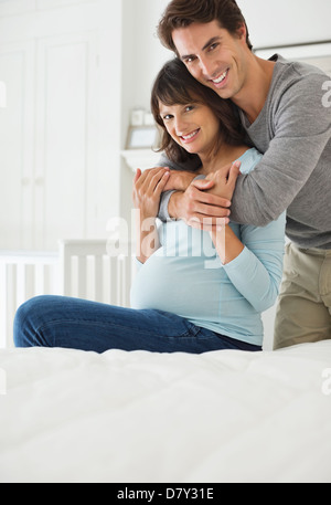 Man hugging pregnant girlfriend on bed Banque D'Images