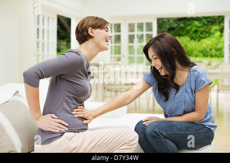 Woman holding pregnant friend's belly Banque D'Images