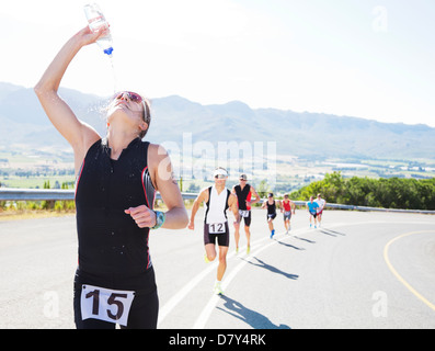 Runner spraying water on rural road Banque D'Images