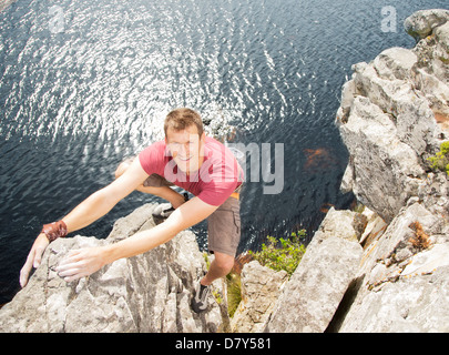 Climber scaling falaise côtière Banque D'Images