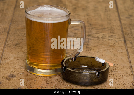 Bière et cigarette sur une table en bois Banque D'Images