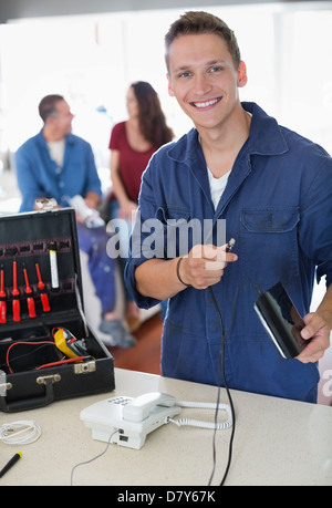 Electrician working on telephone in home Banque D'Images