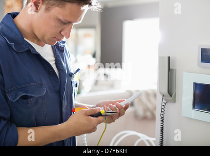 Electrician working on telephone in home Banque D'Images