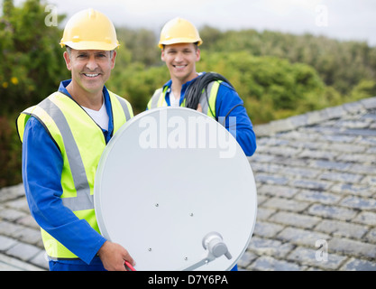 L'installation de travailleurs antenne parabolique sur le toit Banque D'Images