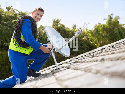 L'installation de travailleurs antenne parabolique sur le toit Banque D'Images