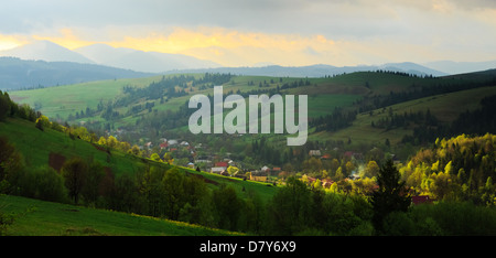 Matin de printemps paysage rural dans les Carpates. Ciel dramatique avant l'aube, rayon de soleil d'essayer de briser le clo Banque D'Images