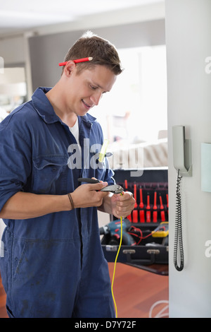 Electrician working on telephone in home Banque D'Images