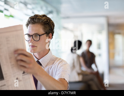 Businessman reading newspaper in office Banque D'Images