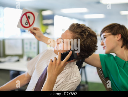 Businesswoman showing 'pas de téléphones cellulaires' signe à collègue Banque D'Images