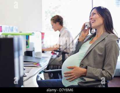 Pregnant businesswoman talking on telephone Banque D'Images