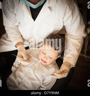 Caucasian dentist examinant les dents du garçon in office Banque D'Images