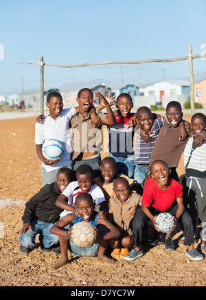 Boys holding soccer balls in dirt field Banque D'Images