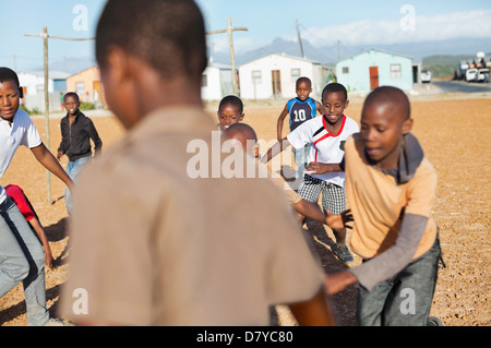 Boys playing soccer together in dirt field Banque D'Images