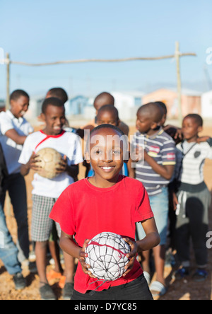 Boys holding soccer balls in dirt field Banque D'Images